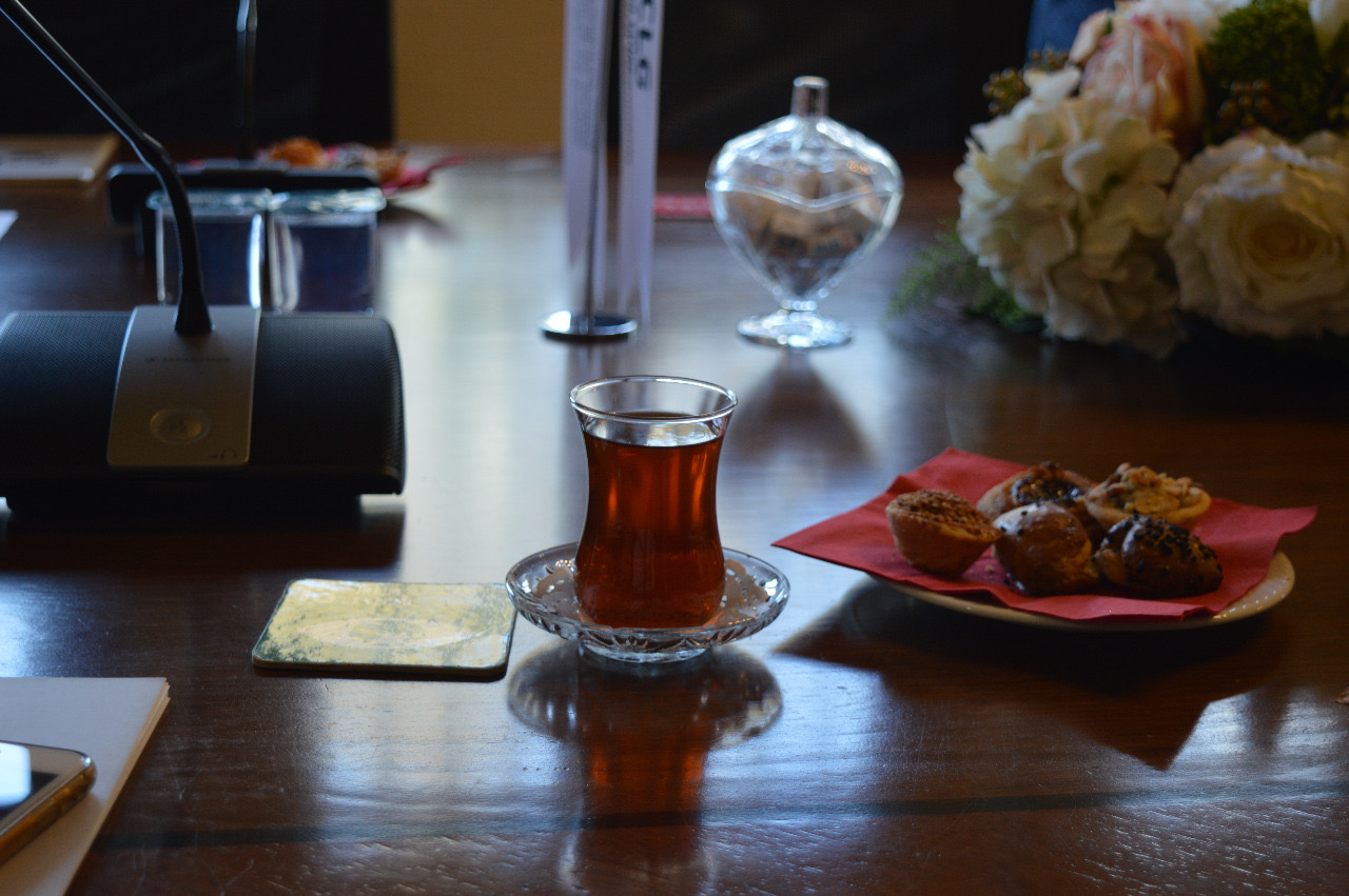 Teekuppi ja leivonnaisia kokouspöydällä.